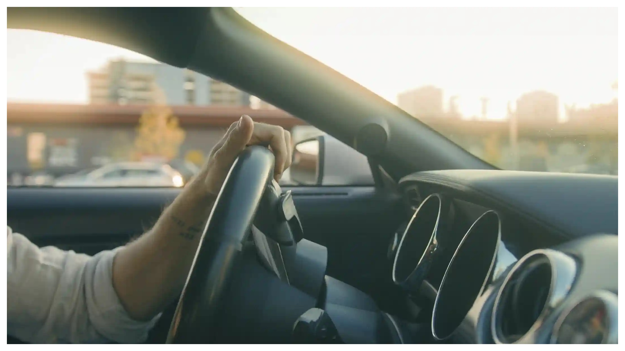Persona conduciendo un auto con atardecer de fondo